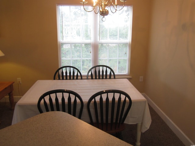 carpeted dining room featuring a notable chandelier and baseboards