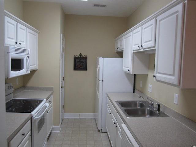 kitchen with white appliances, visible vents, white cabinets, and a sink