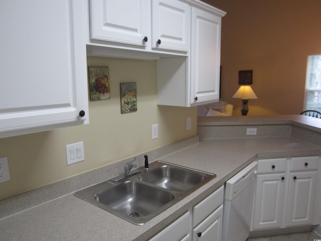 kitchen with a peninsula, white dishwasher, white cabinetry, and a sink