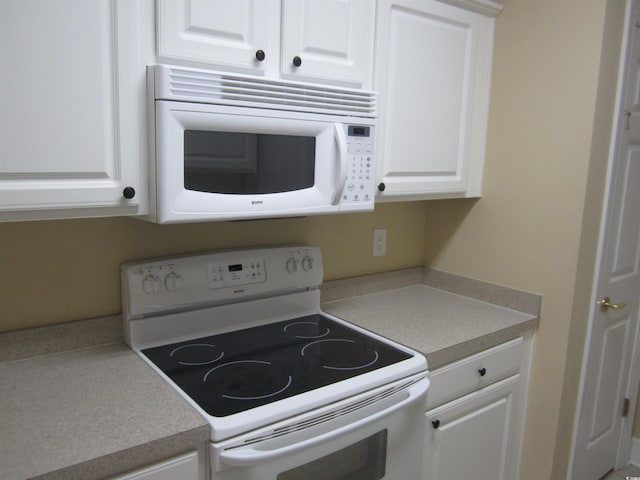 kitchen with light countertops, white appliances, and white cabinets