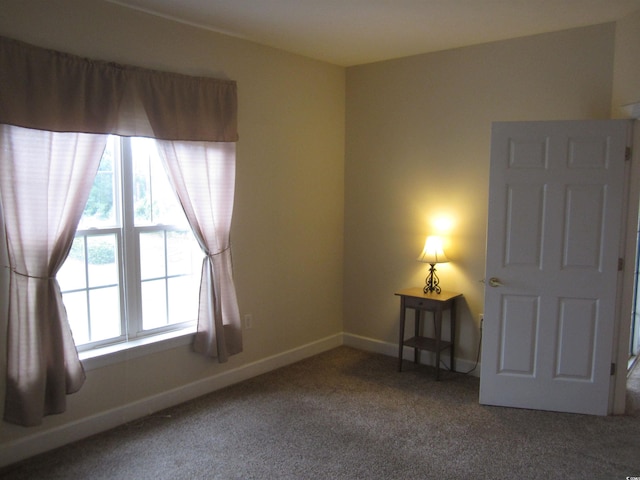 carpeted empty room featuring baseboards