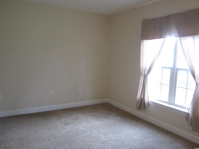 empty room featuring carpet and baseboards