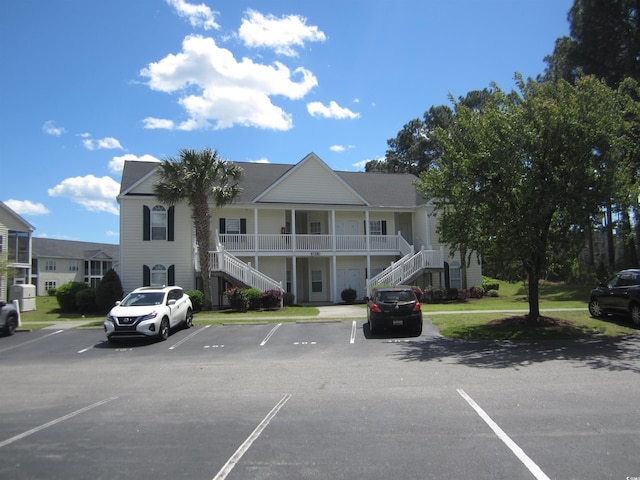 view of property with stairs and uncovered parking