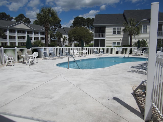 community pool with a patio and fence