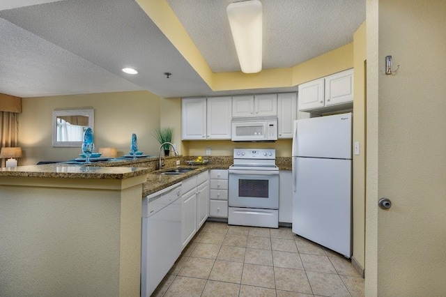 kitchen with white cabinets, sink, kitchen peninsula, light tile patterned flooring, and white appliances