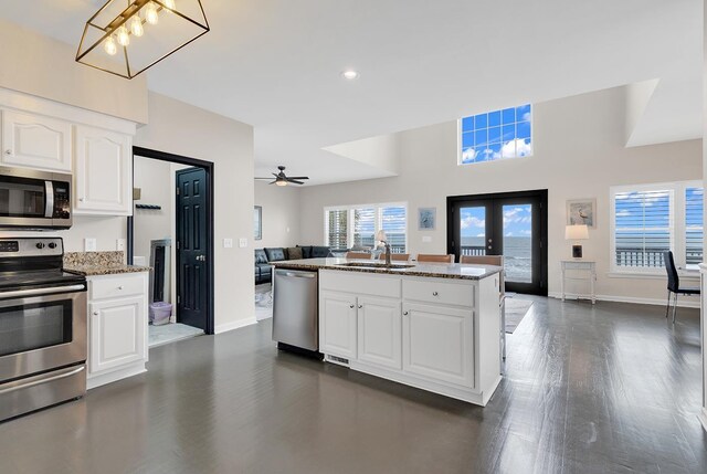 kitchen featuring appliances with stainless steel finishes, white cabinetry, stone counters, and dark hardwood / wood-style floors