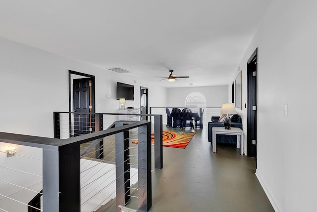 corridor featuring visible vents, finished concrete flooring, an upstairs landing, and baseboards