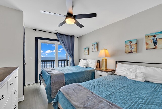 bedroom featuring ceiling fan, a water view, access to outside, and light wood-type flooring