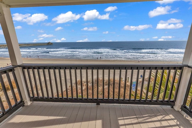 wooden deck featuring a water view and a view of the beach