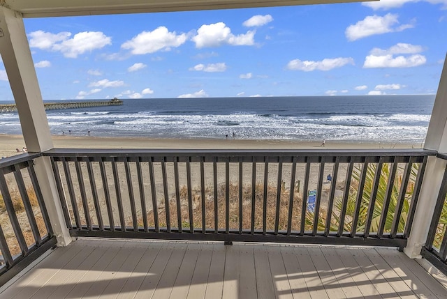 wooden deck featuring a view of the beach and a water view