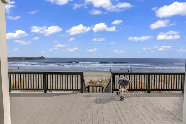 wooden terrace featuring a beach view and a water view