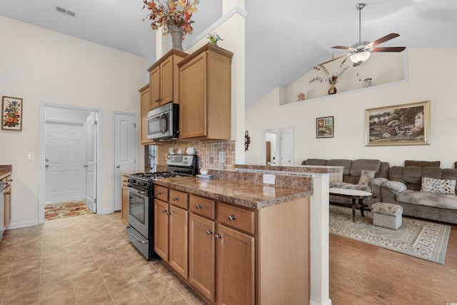 kitchen with high vaulted ceiling, tasteful backsplash, stainless steel appliances, kitchen peninsula, and ceiling fan