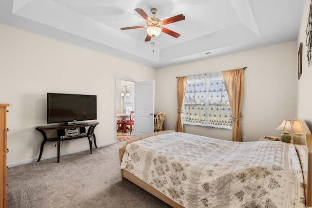 carpeted bedroom featuring a raised ceiling and ceiling fan