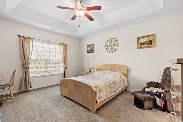 carpeted bedroom featuring ceiling fan and a raised ceiling