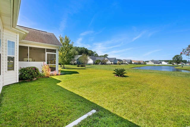 view of yard featuring a water view and a sunroom