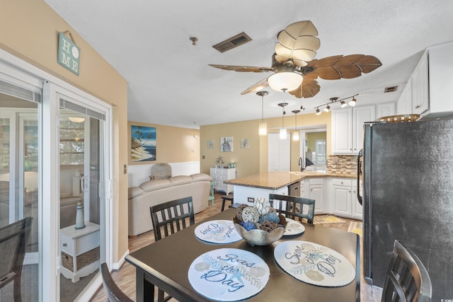 dining area with ceiling fan, rail lighting, light hardwood / wood-style flooring, and a healthy amount of sunlight