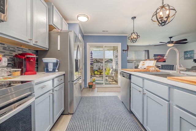 kitchen featuring decorative backsplash, stainless steel appliances, decorative light fixtures, and light hardwood / wood-style flooring