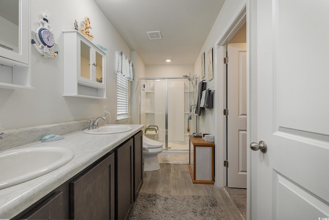 bathroom with hardwood / wood-style flooring, a shower with shower door, vanity, and toilet