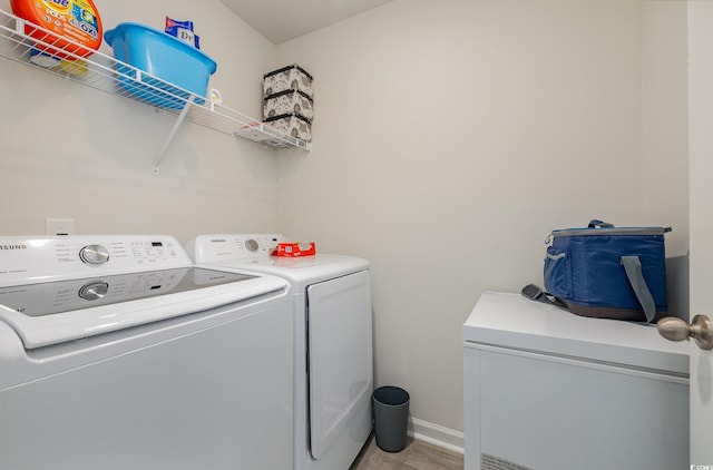 clothes washing area with washing machine and clothes dryer and light hardwood / wood-style floors