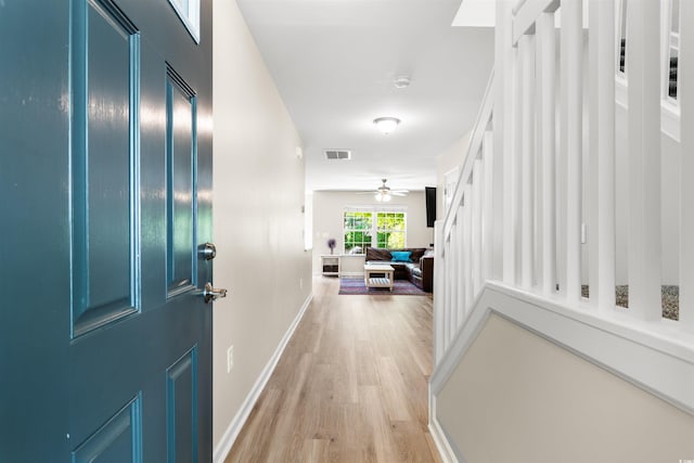 foyer entrance with light wood finished floors, baseboards, visible vents, and a ceiling fan