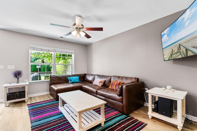 living room featuring a ceiling fan, baseboards, and wood finished floors