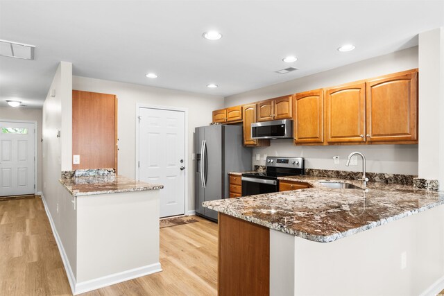 kitchen with dark stone counters, light hardwood / wood-style floors, and stainless steel appliances