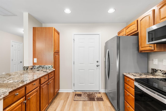 kitchen with stainless steel microwave, light wood-type flooring, visible vents, and light stone countertops