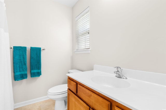 bathroom with toilet, baseboards, vanity, and tile patterned floors