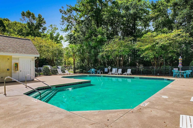 community pool with a patio area and fence