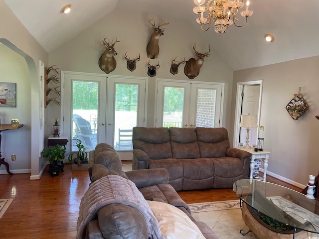 living room featuring hardwood / wood-style floors, high vaulted ceiling, french doors, and a notable chandelier