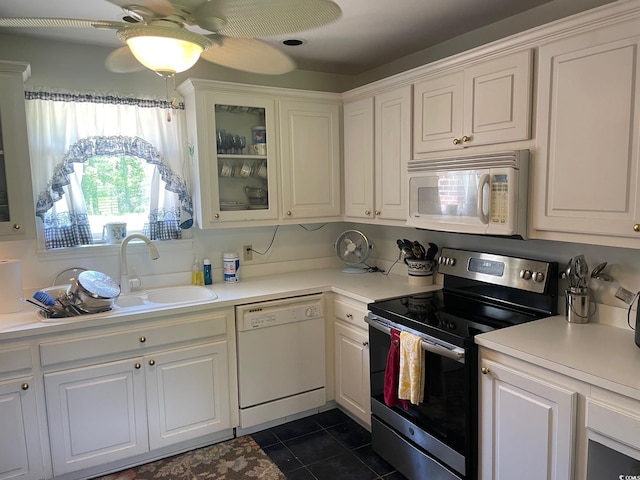 kitchen featuring white appliances, ceiling fan, dark tile patterned flooring, and white cabinets