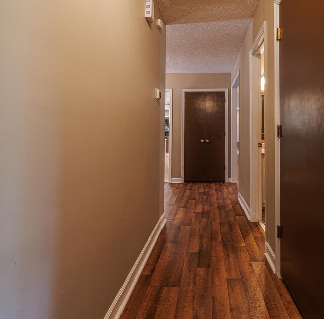 hallway with a textured ceiling and dark wood-type flooring