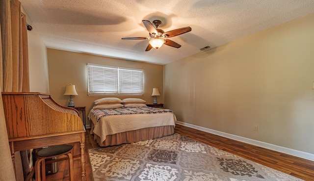 bedroom with visible vents, baseboards, a ceiling fan, wood finished floors, and a textured ceiling