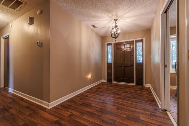 foyer entrance with a notable chandelier, a textured ceiling, and dark hardwood / wood-style floors