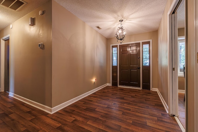 foyer entrance featuring dark wood-style flooring, visible vents, a textured ceiling, and baseboards