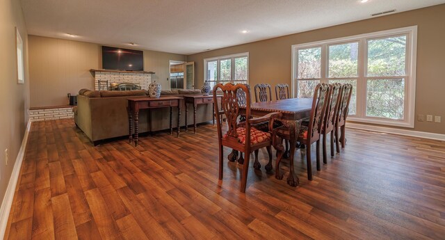 dining area with dark hardwood / wood-style flooring and a brick fireplace