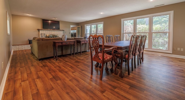 dining room with baseboards, a fireplace, visible vents, and dark wood finished floors