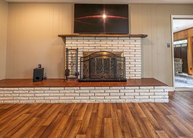 details featuring wood walls, wood-type flooring, and a brick fireplace