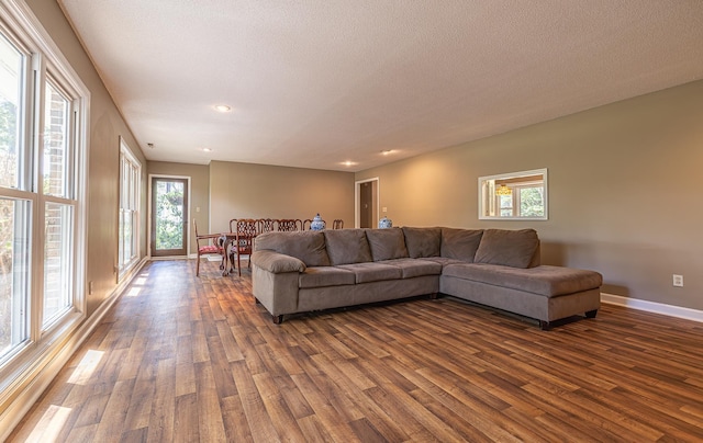 living room featuring a textured ceiling, baseboards, and dark wood-style flooring