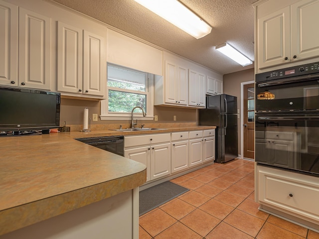 kitchen with light tile patterned floors, light countertops, white cabinetry, a sink, and black appliances