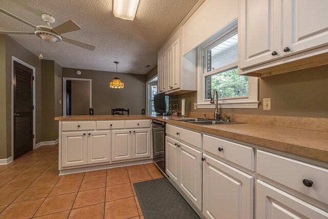 kitchen with white cabinetry, sink, light tile patterned floors, kitchen peninsula, and hanging light fixtures