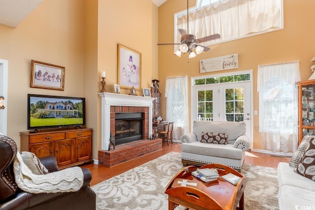 living room with high vaulted ceiling, wood-type flooring, a fireplace, and ceiling fan