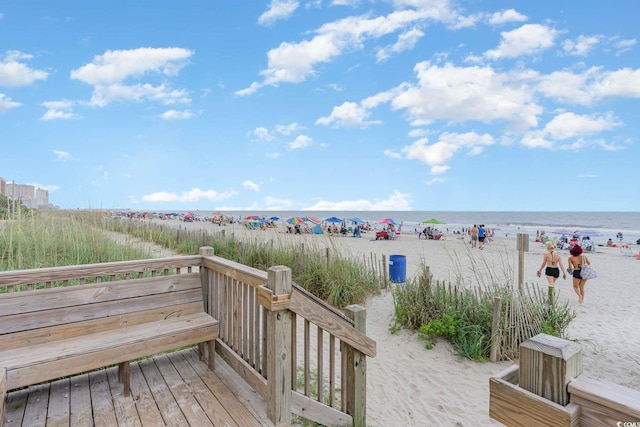 wooden deck featuring a water view and a view of the beach