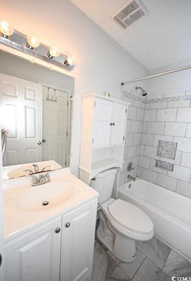 full bathroom with tiled shower / bath, vanity, and toilet