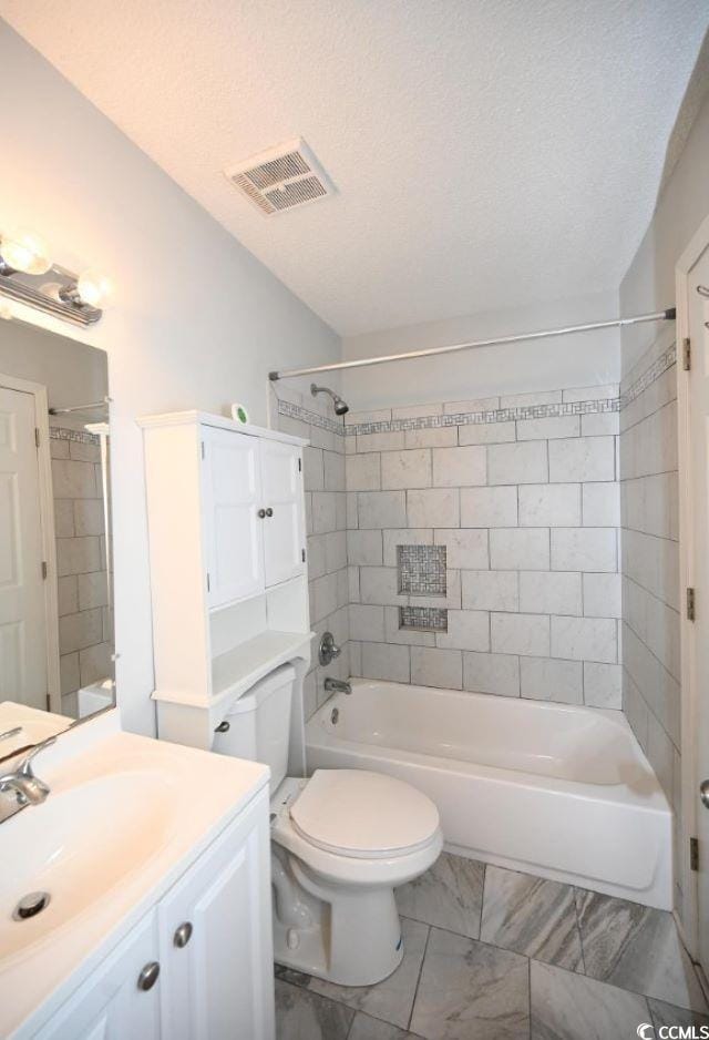 full bathroom with a textured ceiling, tiled shower / bath combo, vanity, and toilet