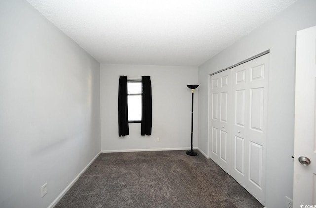 unfurnished bedroom featuring dark carpet and a closet