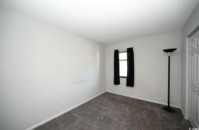 empty room with dark carpet and a textured ceiling