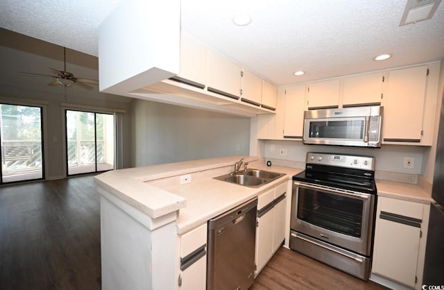 kitchen featuring dark hardwood / wood-style floors, sink, kitchen peninsula, appliances with stainless steel finishes, and ceiling fan