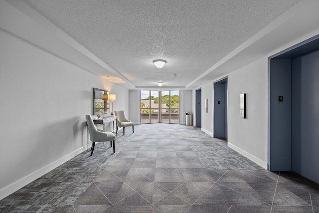 interior space with a textured ceiling, elevator, and dark tile patterned flooring