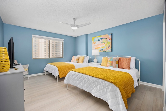 bedroom with light hardwood / wood-style floors, ceiling fan, and a textured ceiling